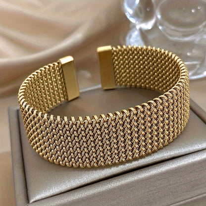Nova bracelete moderna em aço inoxidável entrançado com um toque dourado. Acessório elegante num tom dourado versátil.