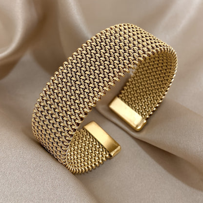 Nova bracelete moderna em aço inoxidável entrançado com um toque dourado. Acessório elegante num tom dourado versátil.