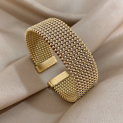 Nova bracelete moderna em aço inoxidável entrançado com um toque dourado. Acessório elegante num tom dourado versátil.