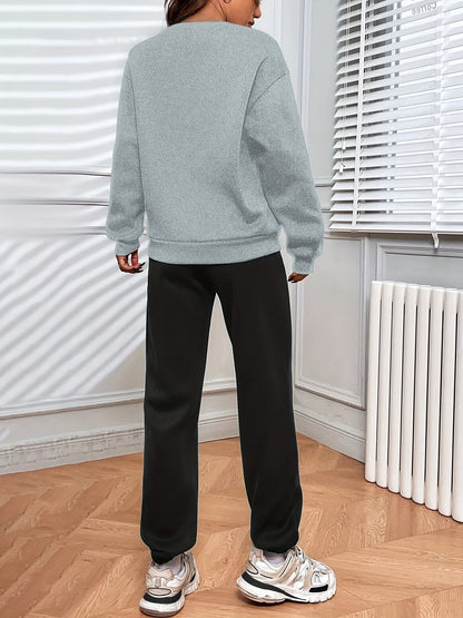 Conjunto casual de duas peças com blocos de cor, composto por uma sweatshirt com estampado de letras e calças jogger desportivas. Roupas femininas.