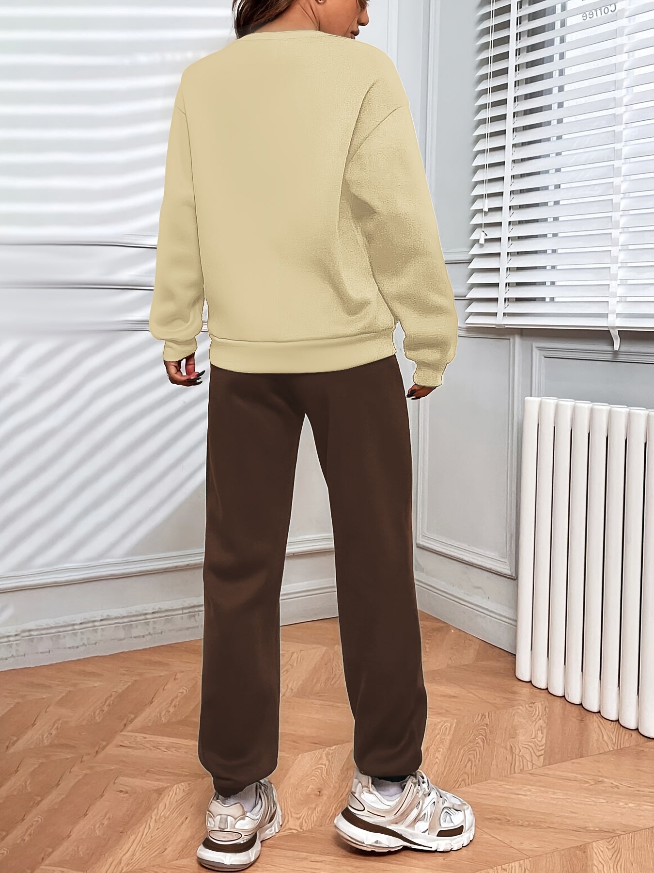 Conjunto casual de duas peças com blocos de cor, composto por uma sweatshirt com estampado de letras e calças jogger desportivas. Roupas femininas.